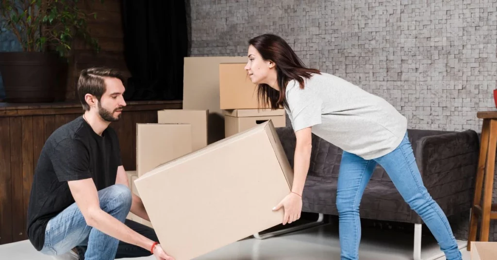 Couple lifting a cardboard box together while preparing for House Moving in Melbourne with Harry The Mover